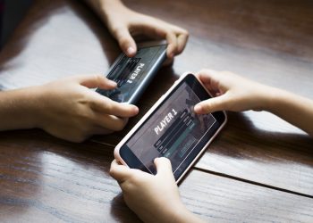 Little boy playing a mobile game against his sister