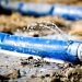 wasting water - water leaking from a hole in a hose. shallow dof with focus on leak